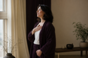 Pokojná žena stojí pri okne a vníma dych pred meditáciou